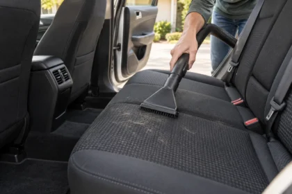 Vacuum upholstery nozzle collecting dog hair from a dark cloth car seat